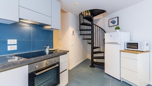 A modern kitchen with a built-in oven, a coffee machine, and a microwave. There is a spiral staircase leading to another level. - Art Apartment at Sanit by Wonderful Italy (Naples)