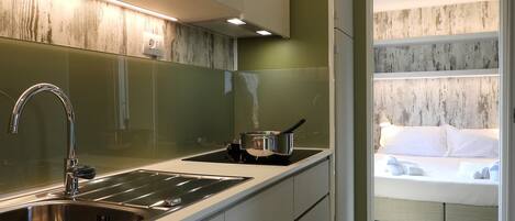 A modern kitchen with a stainless steel sink, a stove, and a pot on the counter.