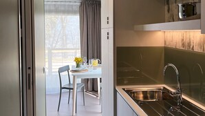 A modern kitchen with a built-in stove, stainless steel sink, and a dining area with a table and chairs. -  Agricampeggio Le Bucoliche (Lazise)