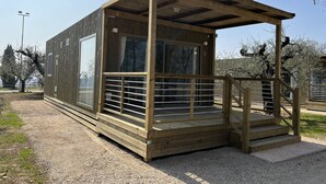 A small wooden cabin with a covered porch and a fenced balcony. -  Agricampeggio Le Bucoliche (Lazise)