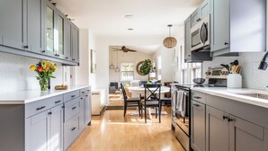 Una cocina moderna con armarios grises, una isla central y un comedor con ventilador de techo.