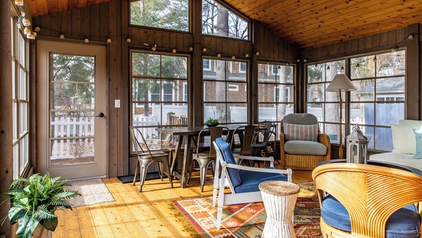 Una cabaña de madera acogedora y bien iluminada, con ventanas amplias, una zona de comedor y un mobiliario confortable.