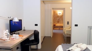A hotel room with a desk, a chair, a bed, and a bathroom visible through an open door.