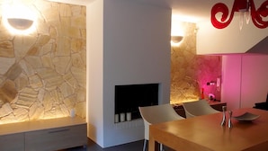 A modern interior with a stone wall, a fireplace, and a dining area.