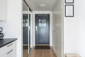 Una cocina moderna con una cafetera, una puerta oscura con felpudo y diplomas enmarcados en la pared.