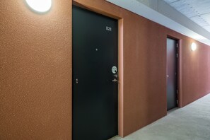 En hall med två svarta dörrar, varav den ena är märkt B28, och en vägg med en tydlig struktur.