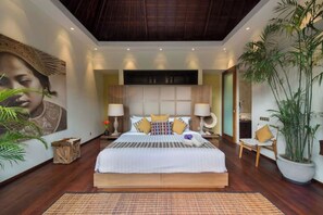 A spacious bedroom with a large bed, two bedside tables, a headboard with built-in lighting, and a large potted plant.