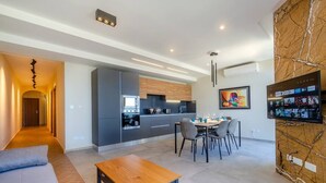 Eine moderne Küche mit integrierten Geräten, ein Essbereich mit Tisch und Stühlen sowie ein Wohnbereich mit Sofa und Couchtisch.