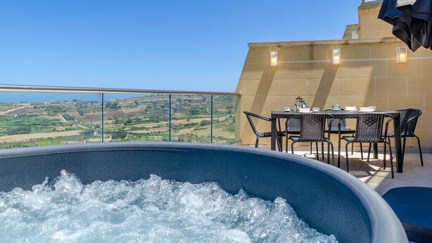 Ein Pool auf dem Dach mit freiem Blick auf die Landschaft, einem Tisch mit Stühlen und einem Glasgeländer.