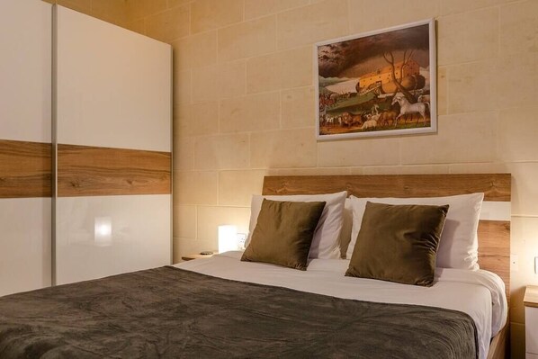 A bedroom with a bed, wooden headboard, and a painting on the wall.