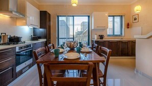 Una cucina moderna con zona pranzo, caratterizzata da un'ampia finestra, mobili in legno ed elettrodomestici in acciaio inossidabile.