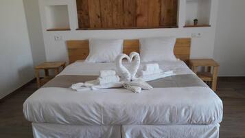 A neatly made bed with white linens and two towels arranged in a heart shape.