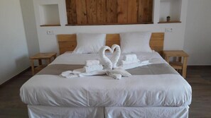 A neatly made bed with white linens and two towels arranged in a heart shape.