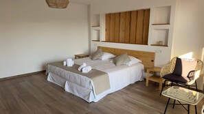 A neatly arranged bedroom with a large bed, bedside tables, a chair, and a wooden headboard.