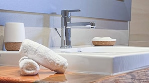 A bathroom with a large mirror, a modern sink, and a towel rack with a rolled towel.