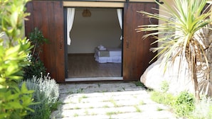 A wooden door leading to a bedroom with a bed and a nightstand. - Résidence La Plage (Porto-Vecchio)