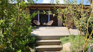 A wooden deck with two wicker chairs and a small table, surrounded by greenery. - Résidence La Plage (Porto-Vecchio)