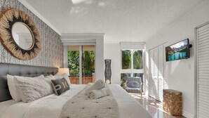 Une chambre avec un grand lit, un miroir, une télévision et une vue sur l’extérieur.