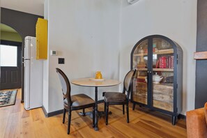 Ein Essbereich mit einem runden Tisch und Stühlen, ein Bücherregal voller Bücher und eine Tür zu einem anderen Raum.