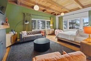 Un dormitorio moderno con una cama grande, un sofá, una mesita de centro y un escritorio con una lámpara.