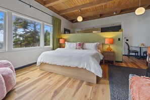A bedroom with a wooden ceiling, a large bed with white bedding, two bedside lamps, and a view of trees through a window. - Ocean Front, The Pink Oyster @ Betty's Beachside, Stairs to the Beach! (Yachats)