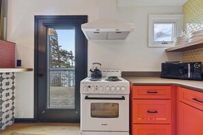A kitchen with a stove, oven, microwave, and a door leading outside. - Ocean Front, The Pink Oyster @ Betty's Beachside, Stairs to the Beach! (Yachats)