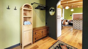 A hallway with a wooden cabinet, a coat rack, and a mirror on the wall. - Ocean Front, The Pink Oyster @ Betty's Beachside, Stairs to the Beach! (Yachats)
