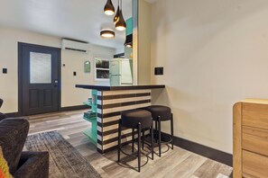Une cuisine compacte équipée d’un réfrigérateur, d’un comptoir-bar et de deux tabourets.