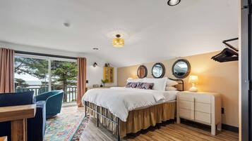 A bedroom with a bed, bedside table, lamp, and a view of the outdoors.