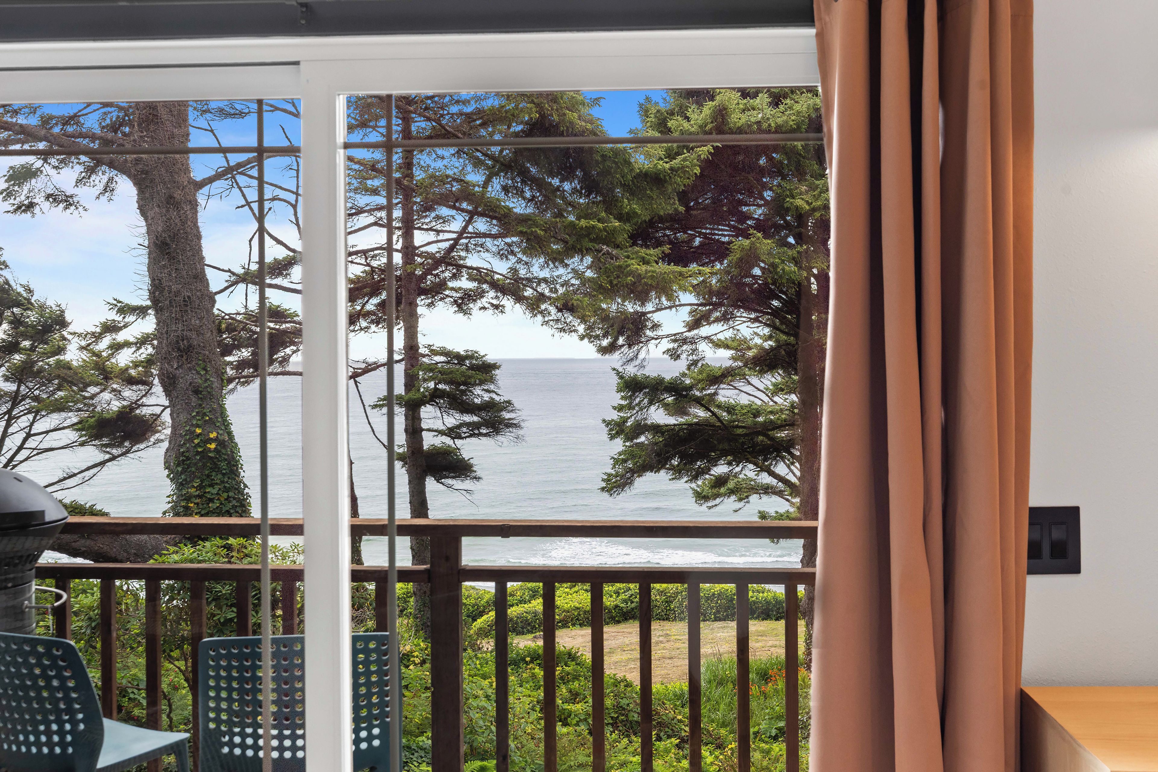 A balcony with a view of the sea and trees.
