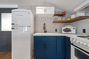 A modern kitchen with a refrigerator, microwave, stove, and blue cabinets.