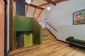 A staircase with wooden steps leading to a landing, a bench, and a wall with a colorful painting. - Ocean Front The Captain's Bounty @ Betty's Beachside, Stairs to the Beach! (Yachats)