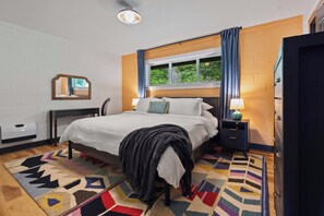 A bedroom with a bed, bedside tables, a window with curtains, a mirror, and a radiator. - Ocean Front The Captain's Bounty @ Betty's Beachside, Stairs to the Beach! (Yachats)