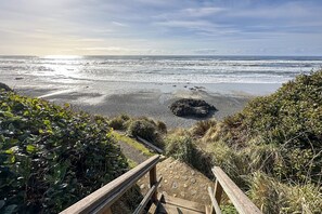A coastal path leading to a beach with a wooden staircase and railings, surrounded by vegetation. - Ocean Front The Captain's Bounty @ Betty's Beachside, Stairs to the Beach! (Yachats)