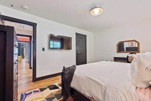 Une chambre d’hôtel avec un lit, une télévision, une porte et un miroir au mur.