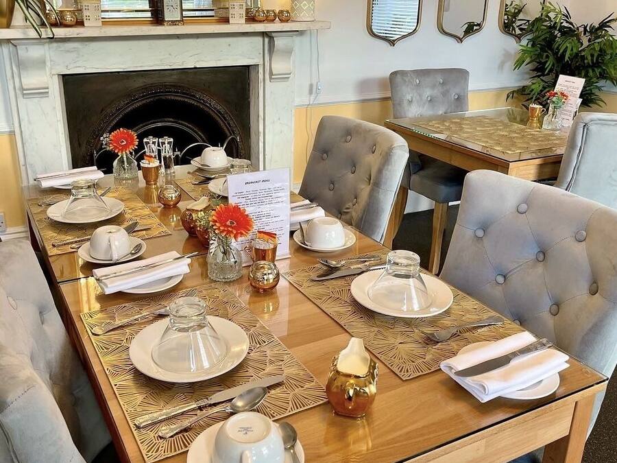 A dining area with a long table set for breakfast, including plates, cutlery, and a menu.