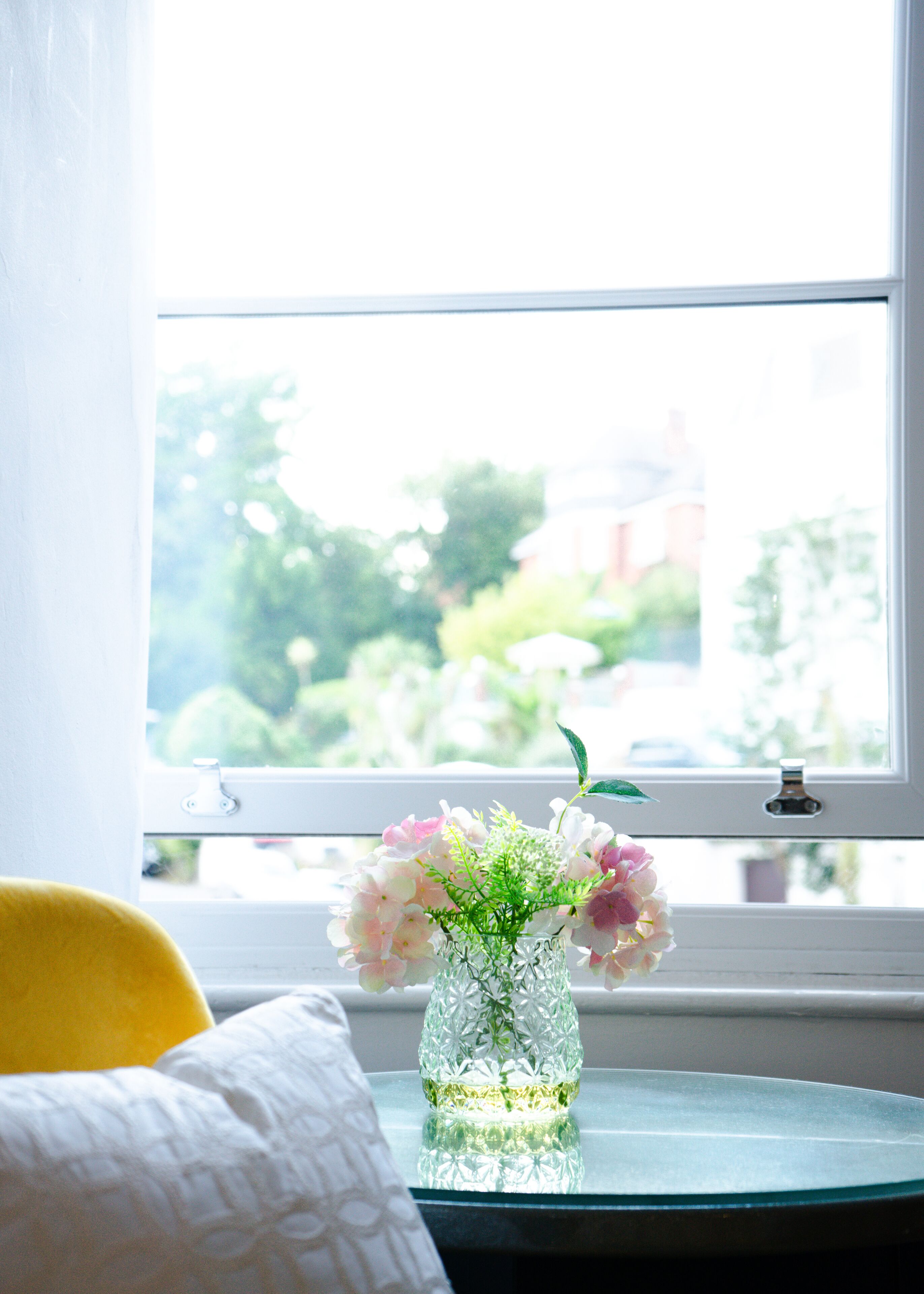 Ein freier Blick auf ein Fenster mit einem Blumenstrauß auf einem Tisch.