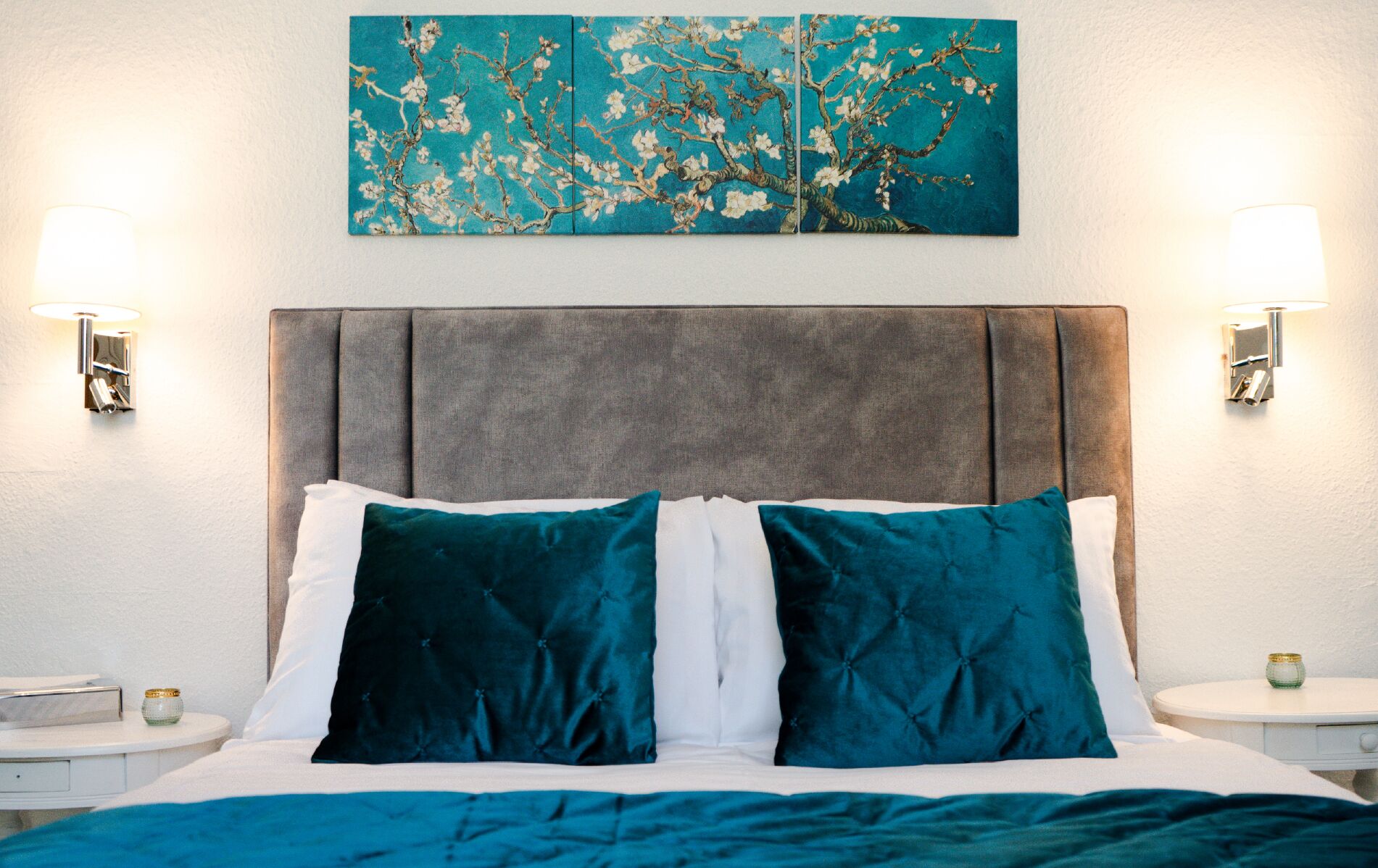 Ein Hotelzimmer mit einem Bett, zwei Nachttischen, einem Wandbild und einer Nachttischlampe.