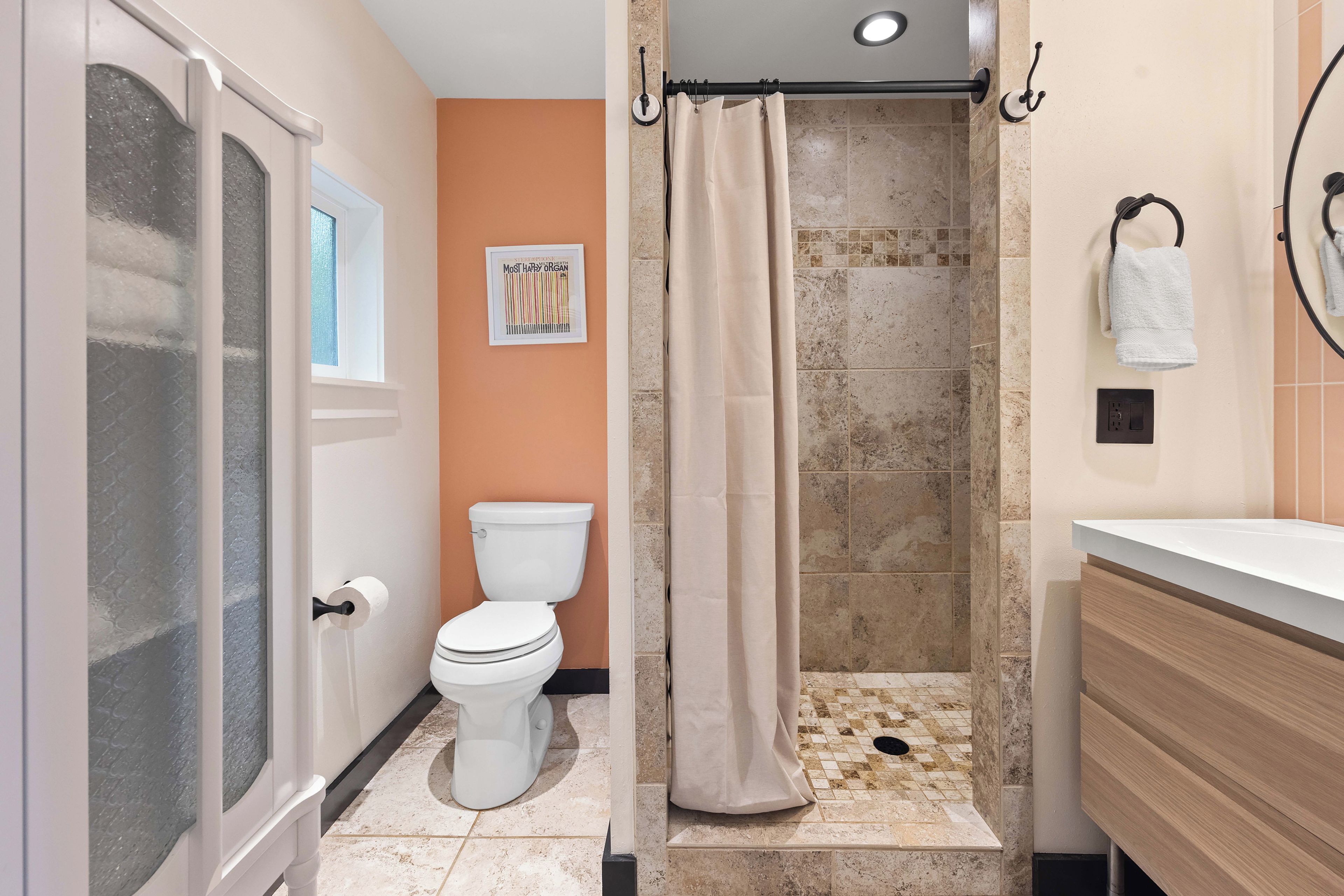 A bathroom with a toilet, shower, and sink.