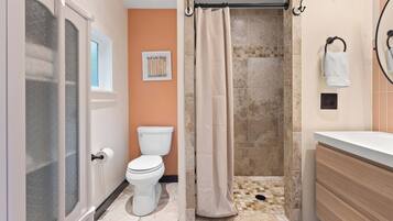 A bathroom with a toilet, shower, and sink.