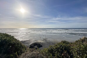 Une plage avec des vagues, un ciel dégagé et le soleil.
