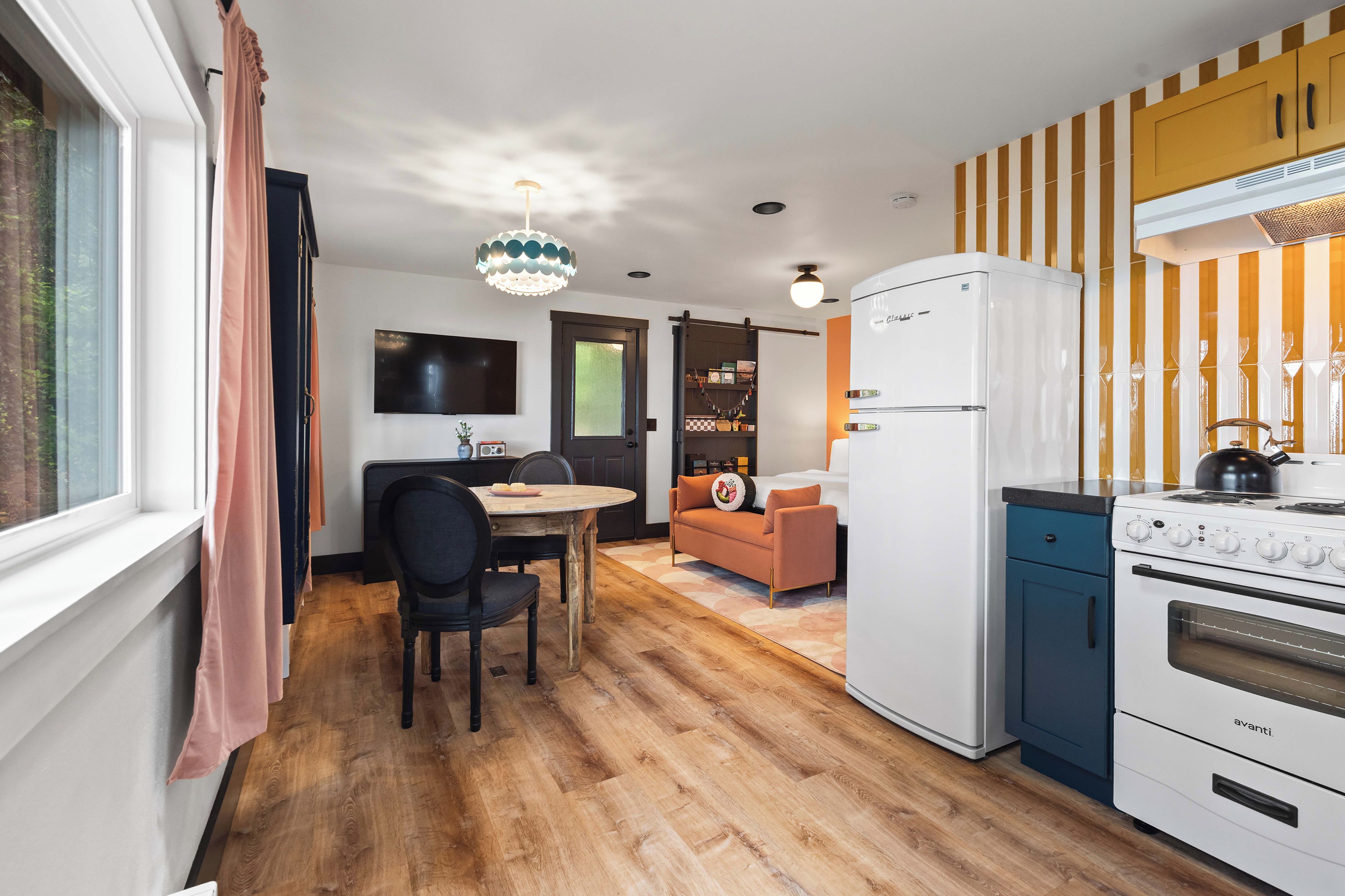A compact kitchen with a refrigerator, stove, and a dining area with a table and chairs.