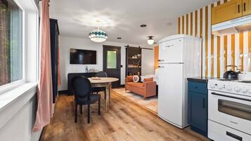 A compact kitchen with a refrigerator, stove, and a dining area with a table and chairs.