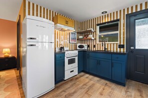 Eine Küche mit Kühlschrank, Herd, Mikrowelle und blauen Schränken.