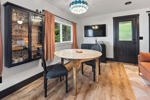 A dining area with a round table, chairs, a cabinet with glass doors, a television, and a door.