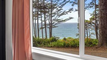 A window with a view of tall trees and a body of water.