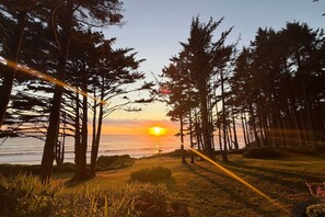 A sunset view with trees and a body of water. - Ocean Front, The Fishwives' Cottage, Stairs to the Beach! (Yachats)