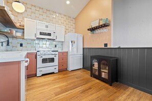 A kitchen with white appliances, wooden cabinets, and a built-in oven. - Ocean Front, The Mighty Mussel House @ Betty's Beachside, Stairs to the Beach! (Yachats)