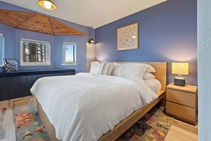 A bedroom with a bed, bedside tables, a nightstand, a wall-mounted lamp, and a ceiling light fixture. - Ocean Front, The Mighty Mussel House @ Betty's Beachside, Stairs to the Beach! (Yachats)