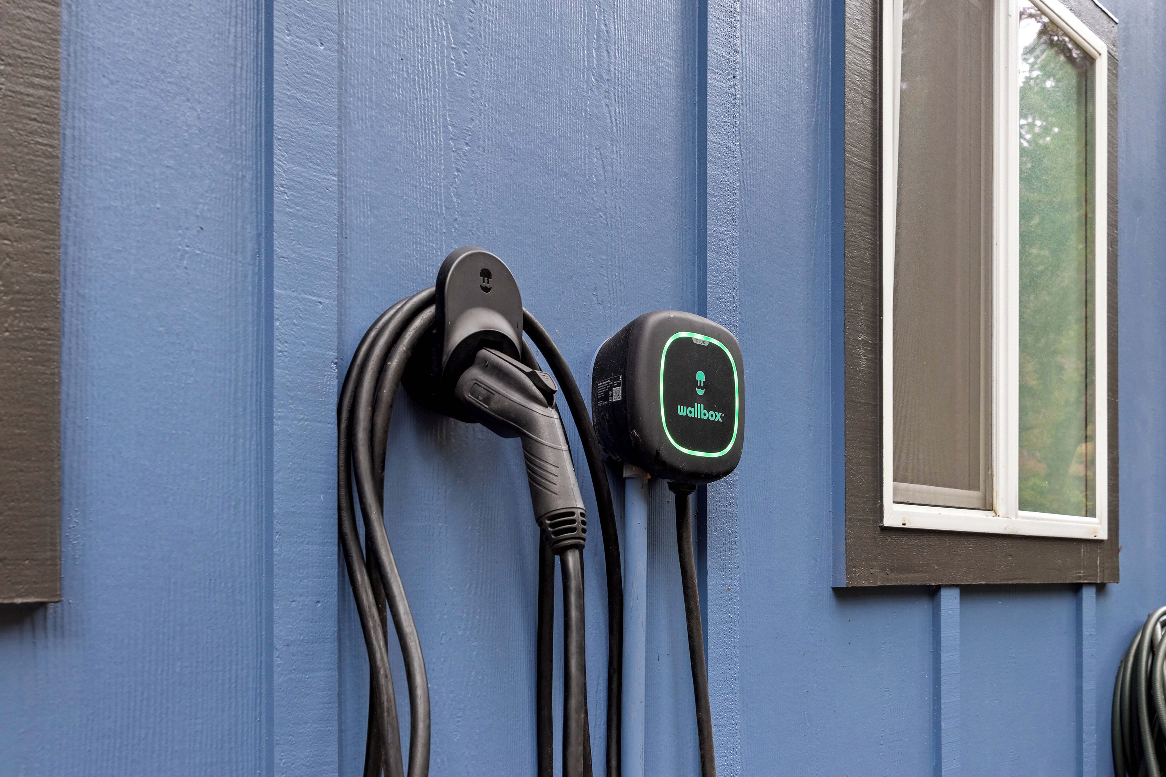 Eine Ladestation für Elektrofahrzeuge an einer Wand, neben der sich ein Fenster befindet.